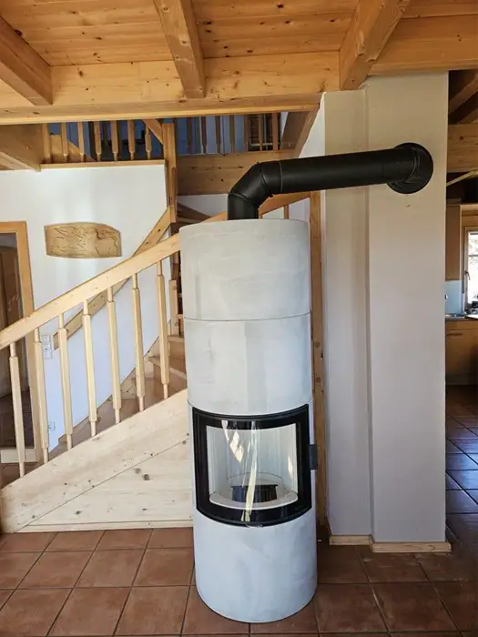 Grauer Ofen vor Holztreppe, gebaut vom Rauchfangkehrermeister Lenk