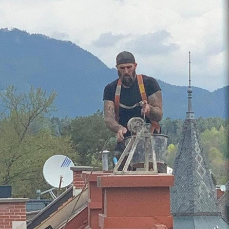 Kaminbau Rauchfangkehrermeister Lenk vor spitzem Dach mit Kübel