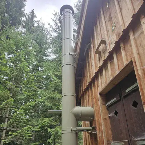 grüner Kamin vor Holzfassade